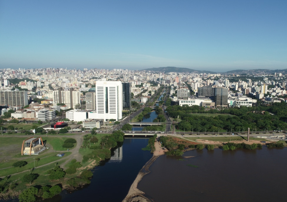 Vista panorâmica do Arroio Dilúvio cortando a Avenida Ipiranga, com edifícios e áreas verdes ao redor, em Porto Alegre, RS.