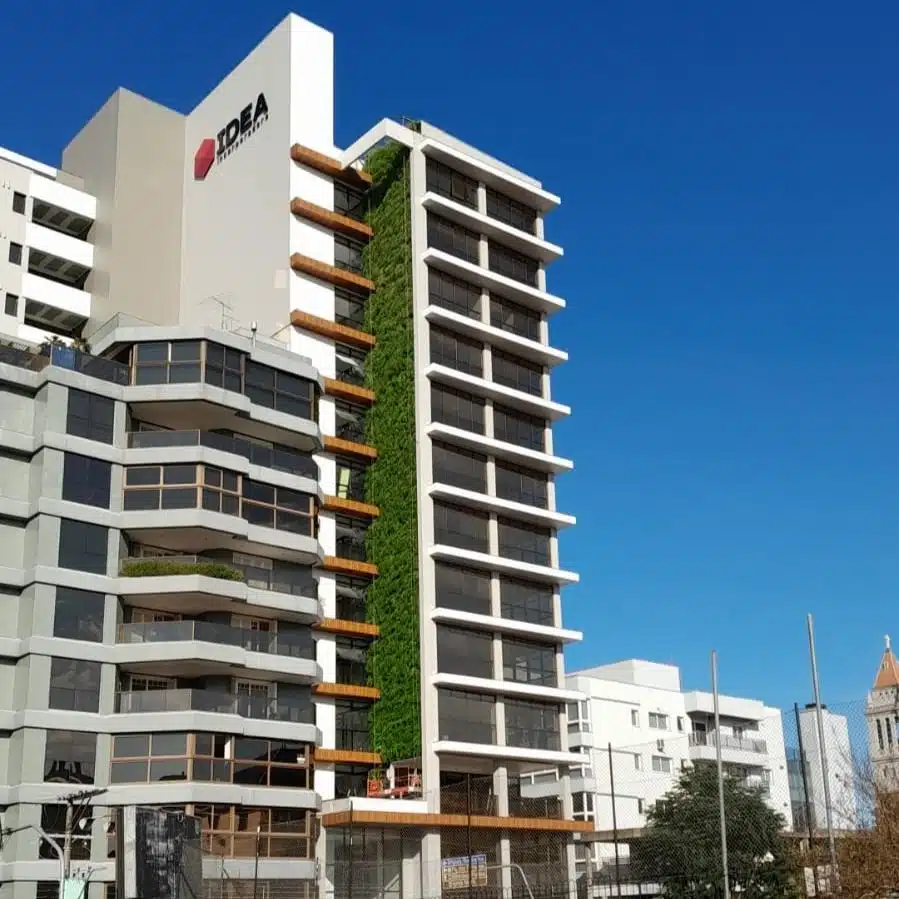 Edifício comercial moderno "IDEA" com um extenso jardim vertical instalado entre as janelas. A solução demonstra o uso do design biofílico para atrair investidores ESG e aumentar a eficiência operacional do imóvel.