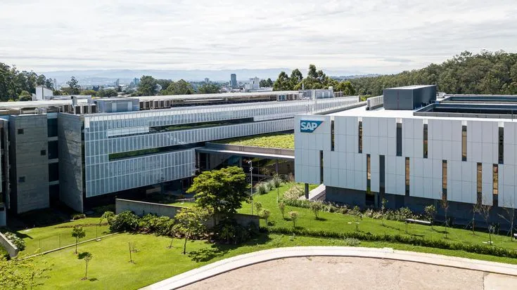 Complexo empresarial da SAP com amplas áreas de gramado e telhados verdes integrados à arquitetura. O projeto exemplifica a aplicação de Soluções Baseadas na Natureza (SBN) para resiliência climática e mitigação de riscos.
