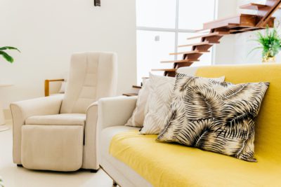 sala com sofá, cadeira confortável e escada em madeira, um exemplo de soluções para conforto térmico