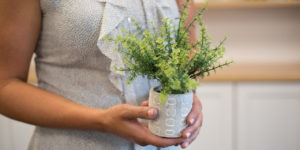 mulher segundando vaso com planta