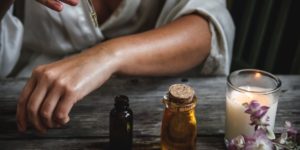 mulher com óleos e velas em cima de uma mesa para simbolizar o que é aromaterapia