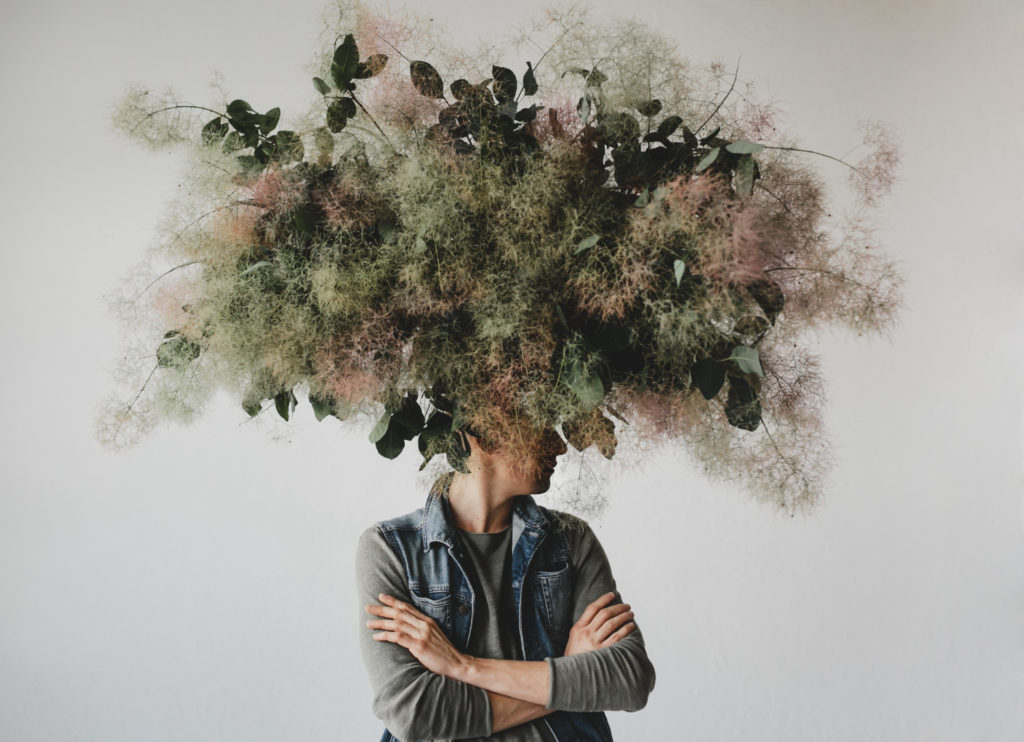Imagem de um mulher de braços cruzados e o cabelo em ilustração de vegetação para simboliozar a psicologia ambiental