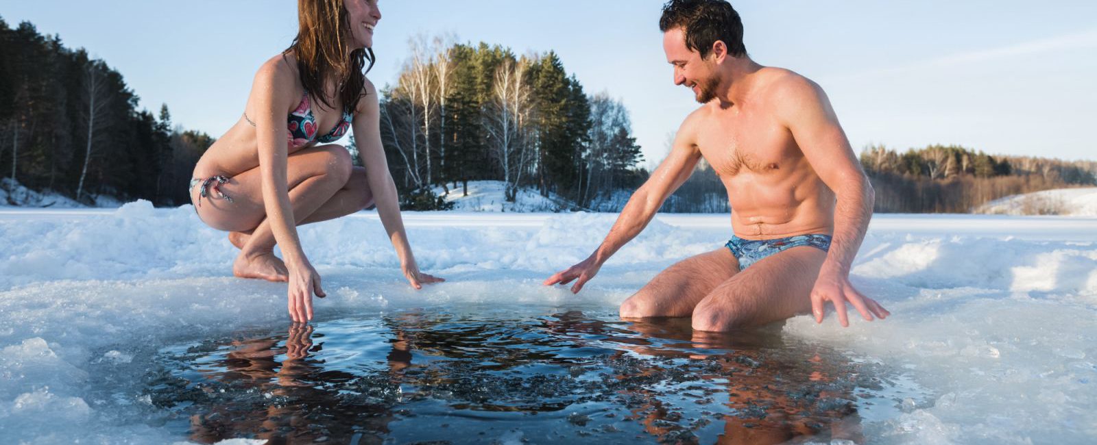 Imagem de um casal com roupa de banho, em uma piscina com gelo, para simbolizar os banhos frios